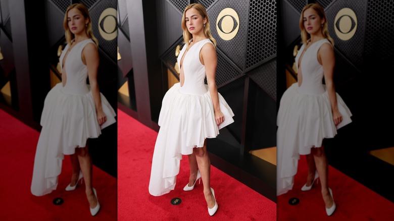 Addison Rae posing in a white high-low dress with deep neckline