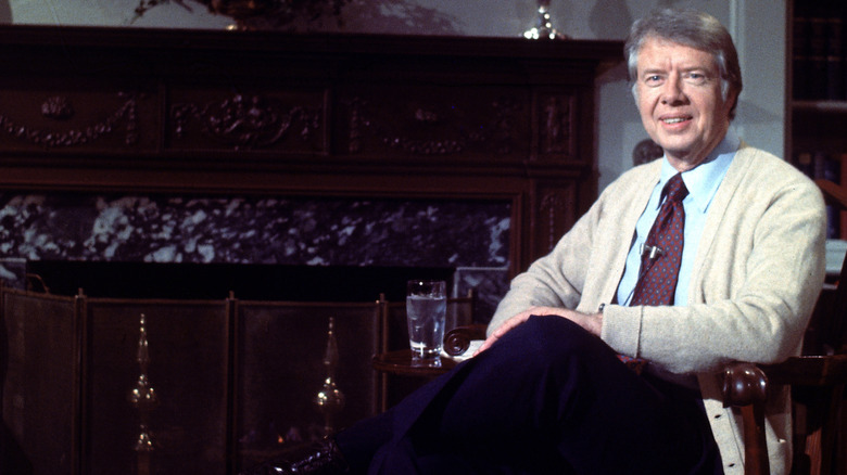 Jimmy Carter smiling in front of a fireplace