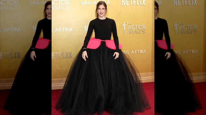 Kathryn Hahn posing in a black and pink gown at the 2026 Actor Awards