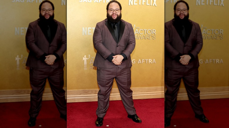 Zach Cherry posing in a brown tux at the 2026 Actor Awards
