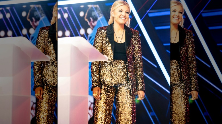 Erika Kirk smiling in a gold sequin outfit onstage at AmericaFest 2025