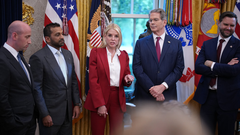 Pam Bondi speaking to others in the Oval Office while wearing a red suit.