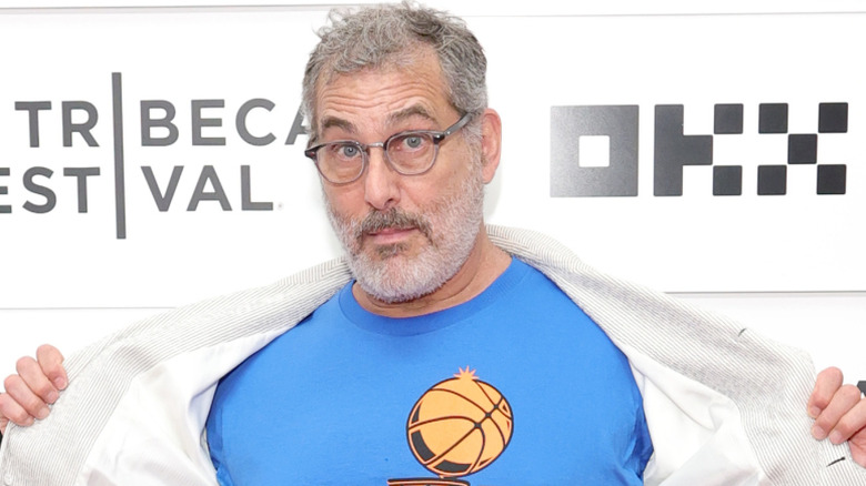 Jonathan Penner holding his jacket open while posing at an event in glasses