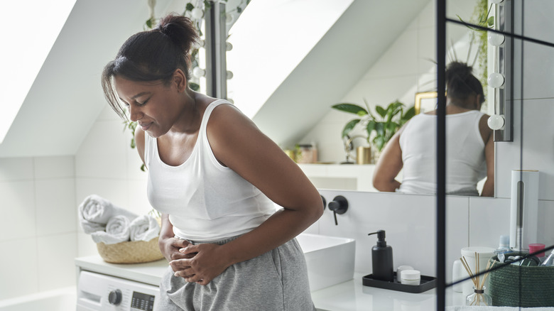 Woman holds stomach because of pain