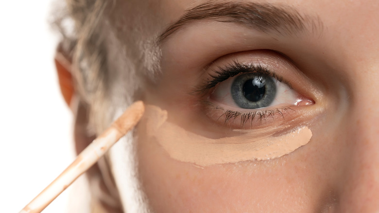 Woman applying undereye concealer