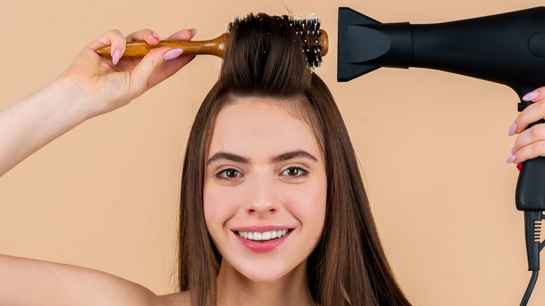 Woman blow drying hair with brush