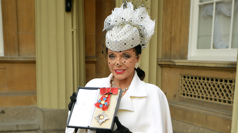Joan Collins (in white) at her Dame ceremony in 2015