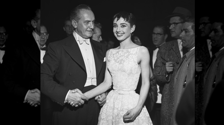 Audrey Hepburn smiles in 1953 and shakes hands with Fredric March at the Academy Awards