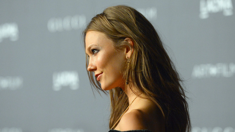 A side-on image of Karlie Kloss smiling against a grey and white backdrop