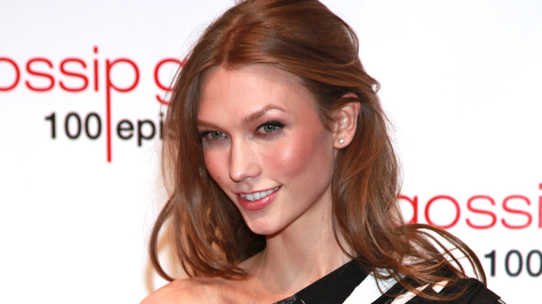 Karlie Kloss smiling for a photo against a promotional backdrop for "Gossip Girl"