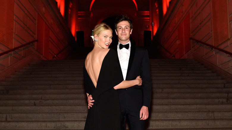 Karlie Kloss and Joshua Kushner embracing on a flight of stairs in black formal wear