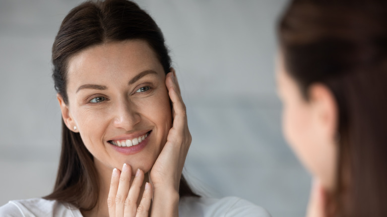 Woman smiling while checking skin