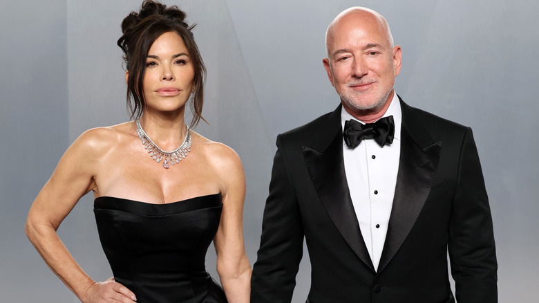 Lauren Sánchez and Jeff Bezos holding hands while posing together in black tie ensembles