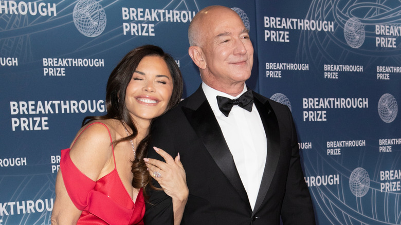 Lauren Sánchez hugging Jeff Bezos' arm while both smile at the Breakthrough Prize event