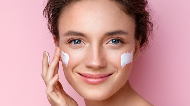 Woman smiles while wearing face cream on cheeks