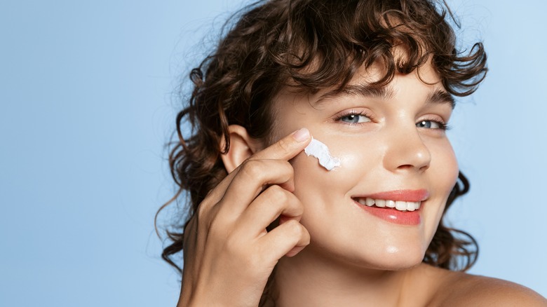 young woman applying moisturizer