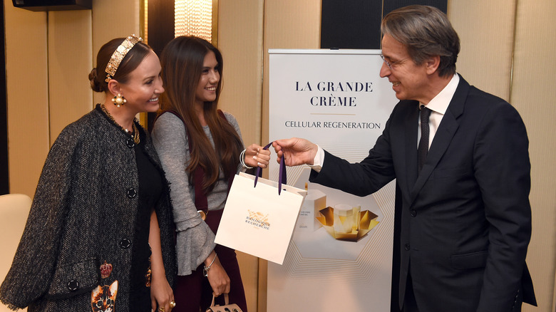 Man handing a Biologique Recherche bag to two women