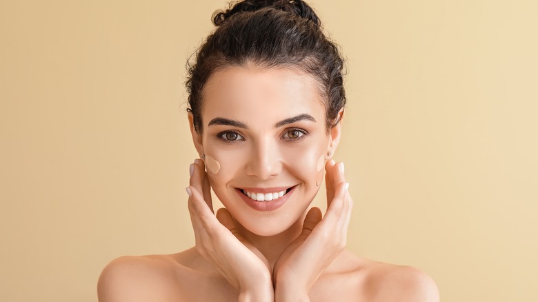 Woman smiling and applying foundation with fingers