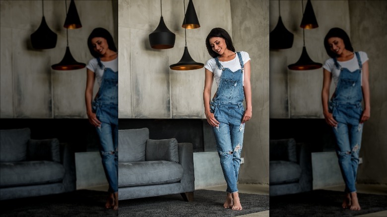 Woman wearing distressed denim overalls