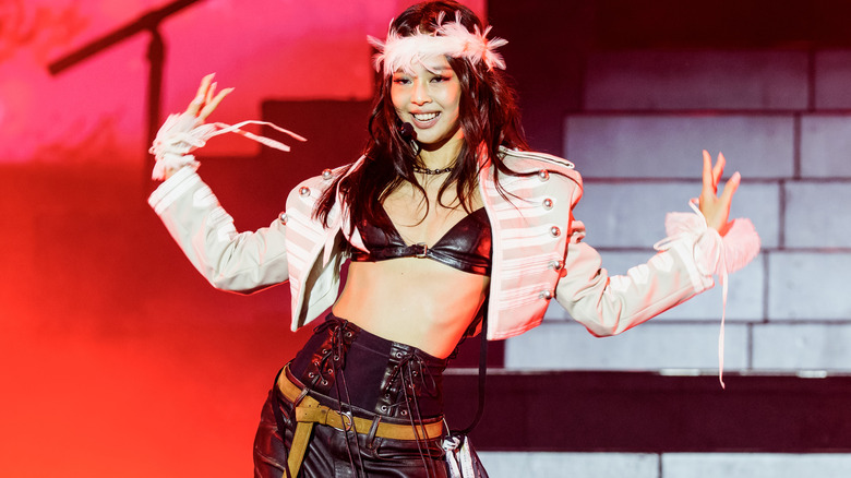 Jennie Kim wearing an old-timey military jacket with a leather bralette, high waisted leather pants, and a feather crown