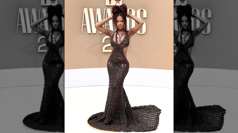 Doechii in a brown dress with her hands on her head, posing at the 2026 BET Awards