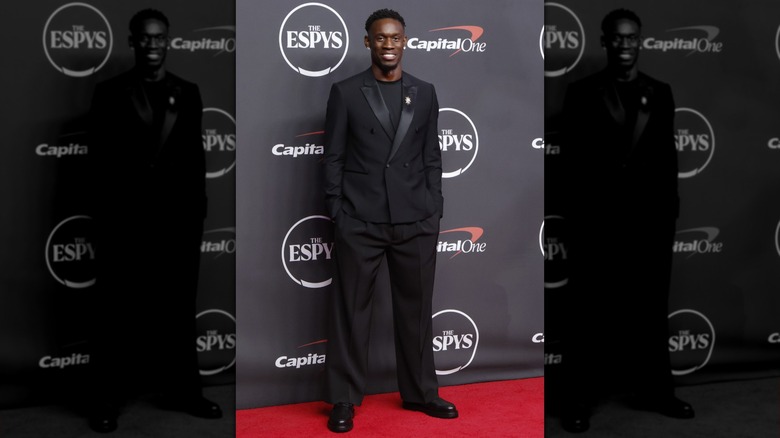 Folarin Balogun with his hands in the pockets of his black suit on the ESPYS red carpet in 2026