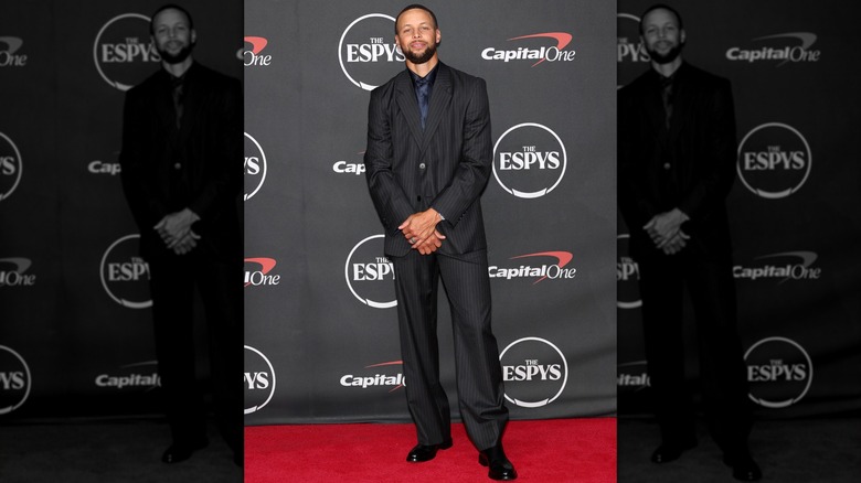 Steph Curry on the ESPYS red carpet in 2026 in a black suit with his hands clasped