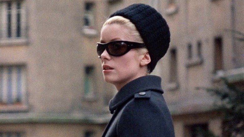 Catherine Deneuve in black sunglasses, a peacoat, and a hat in Belle de Jour (1967).