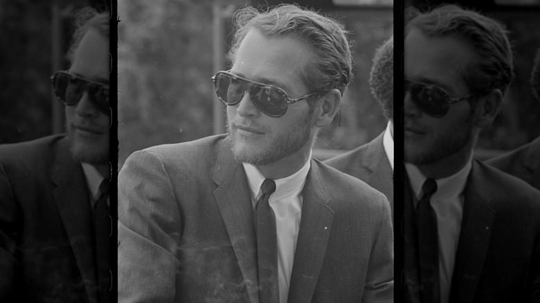 A black and white photograph of Paul Newman in aviator sunglasses and suit in 1963.