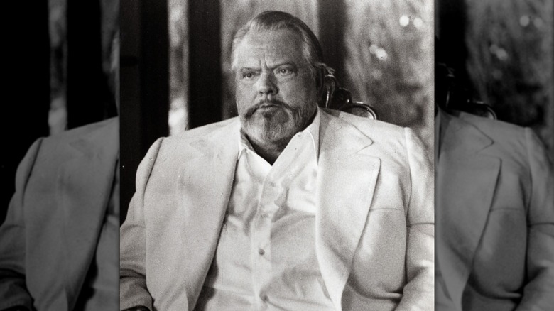 A black and white portrait of Orson Welles wearing a large suit.