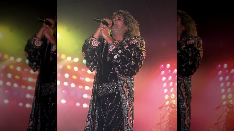 Ozzy Osbourne performing in 1986, wearing a bedazzled black suit with a matching coverup.