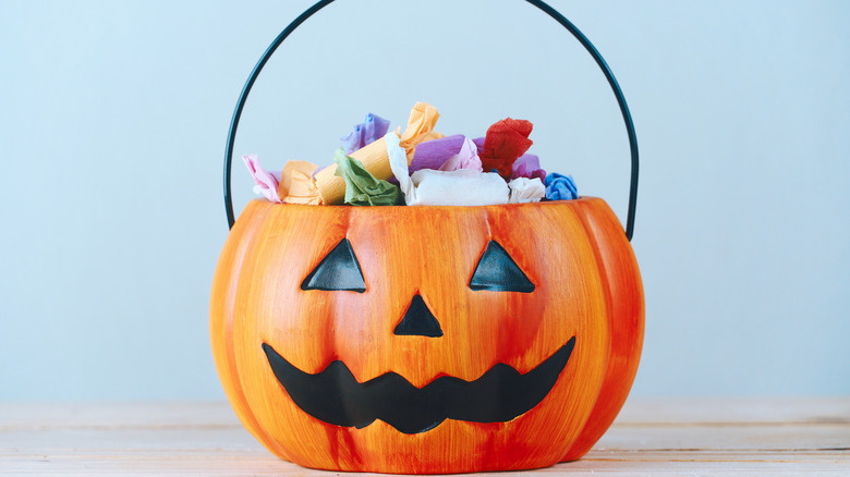 A pumpkin bucket filled with Halloween candy