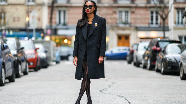 Woman wears tights with a black jacket and sunglasses