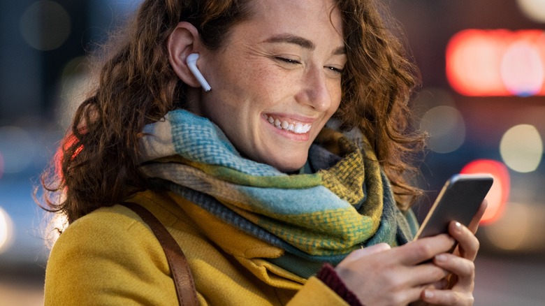 Woman wearing Airpods smiles at phone
