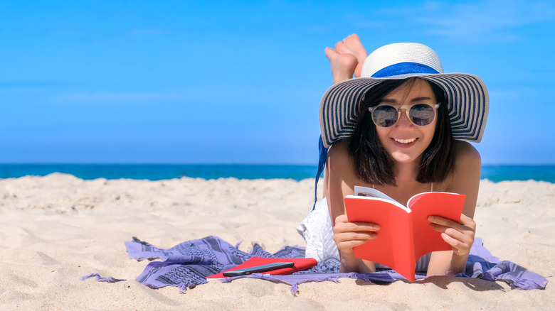 woman reading happily on beach