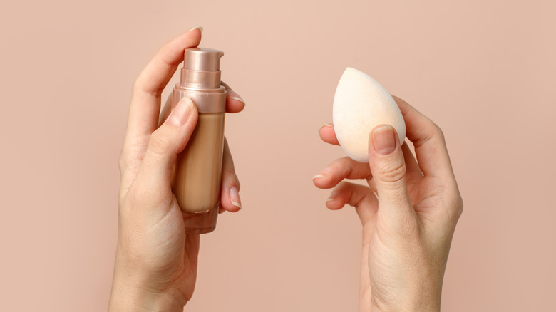 Woman holding a beauty blender and foundation