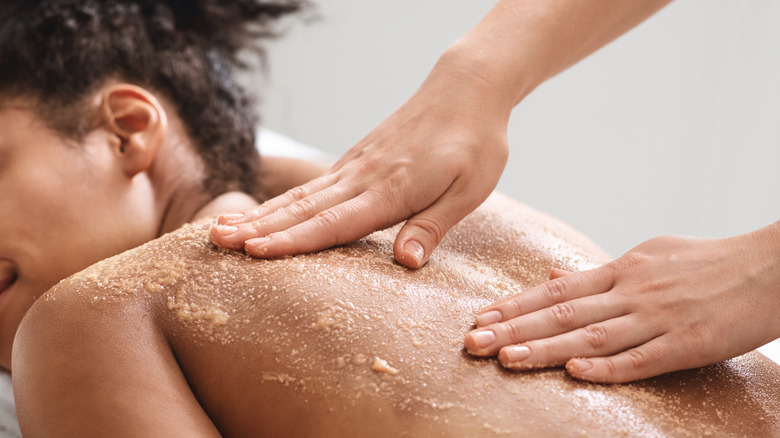 A woman getting an exfoliating scrub on her back