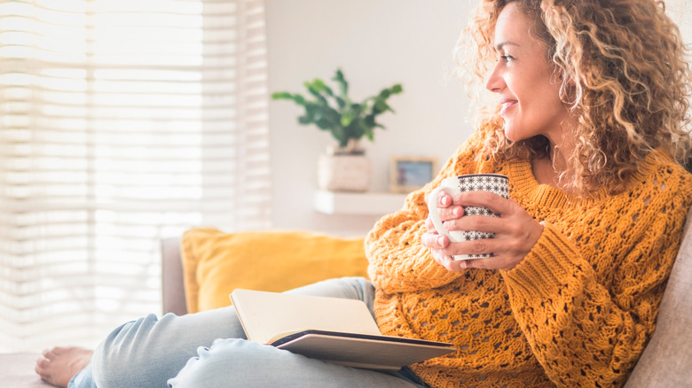 Woman smiling and reading with mug 