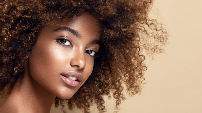 A woman with dark skin wearing bronzer