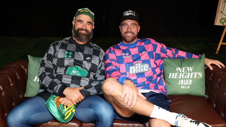 Brothers Jason Kelce and Travis Kelce smiling for a photo from a sofa.