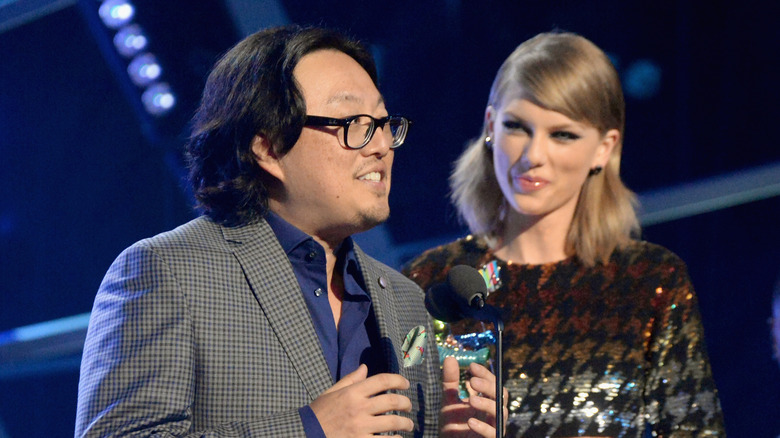 Taylor Swift smiling at Joseph Kahn as he accepts an award onstage.