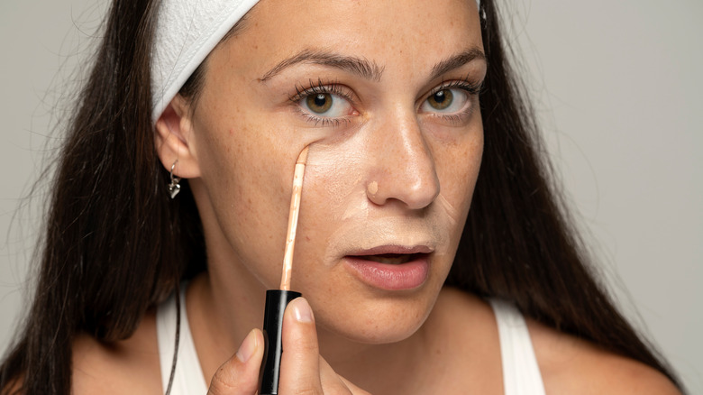 Woman applying concealer under her eyes