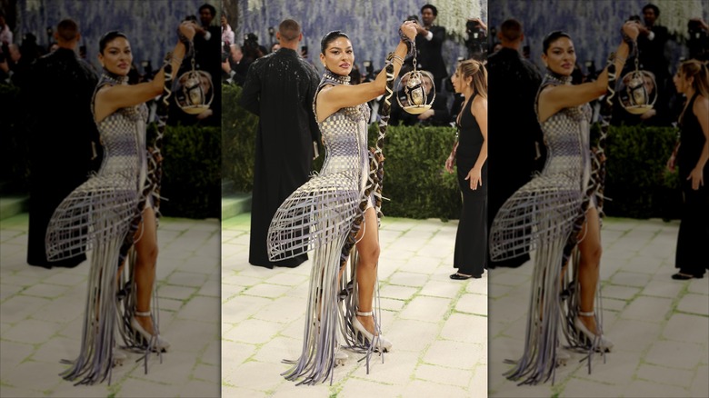 Sabrina Harrison on the 2026 MET Gala red carpet holding up a lantern with a long fake braid in a woven dress