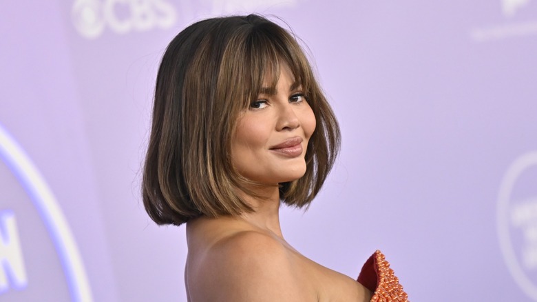 Chrissy Teigen smiling on the red carpet at the 2026 AMAs