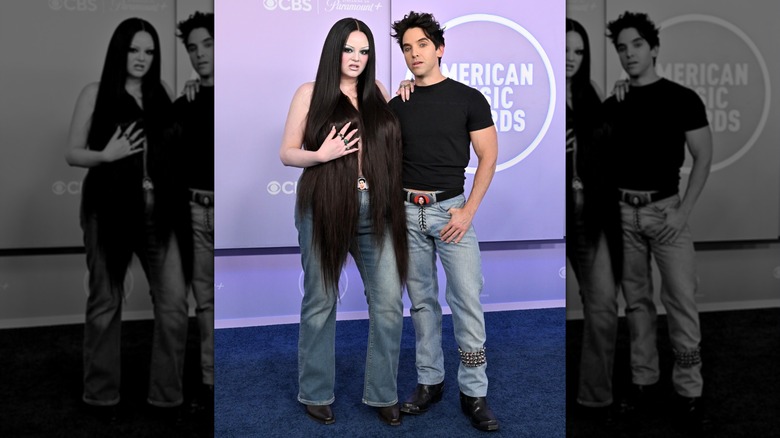 Megan Stalter and Paul W. Downs arm-in-arm, both smizing, on the 2026 AMAs red carpet