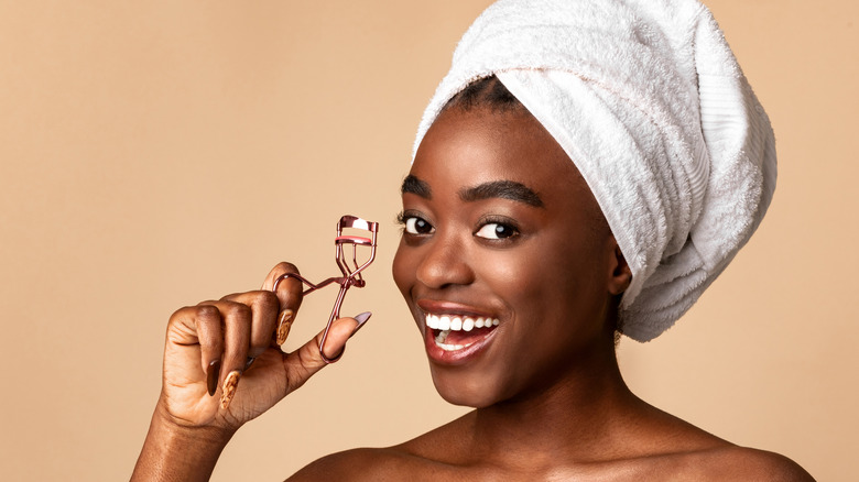 woman using gold eyelash curler