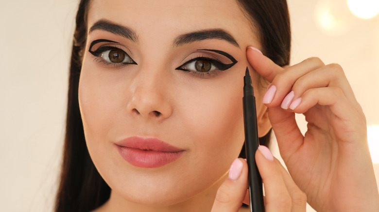 Woman applies eyeliner