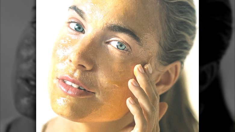 Model with blue eyes and orange skincare