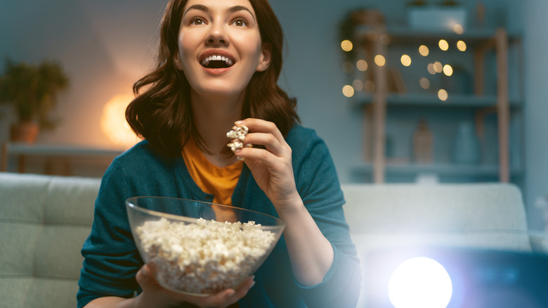 Woman eating popcorn while watching a feel-good film