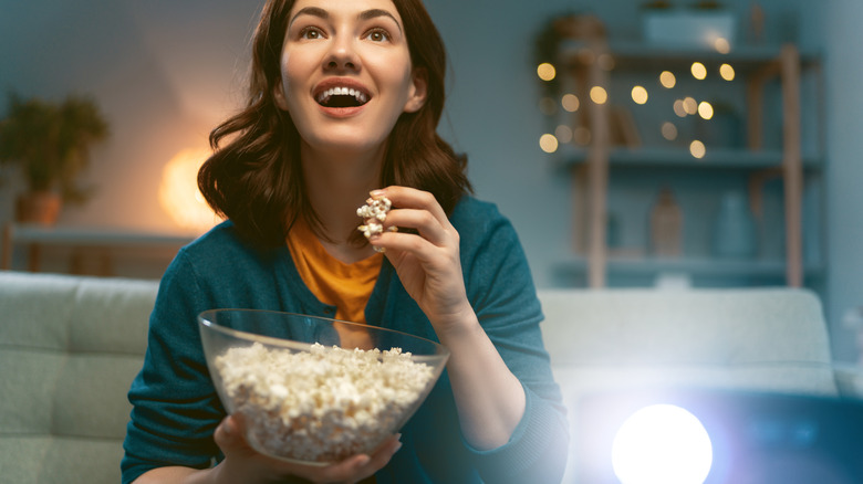 Woman eating popcorn while watching a feel-good film